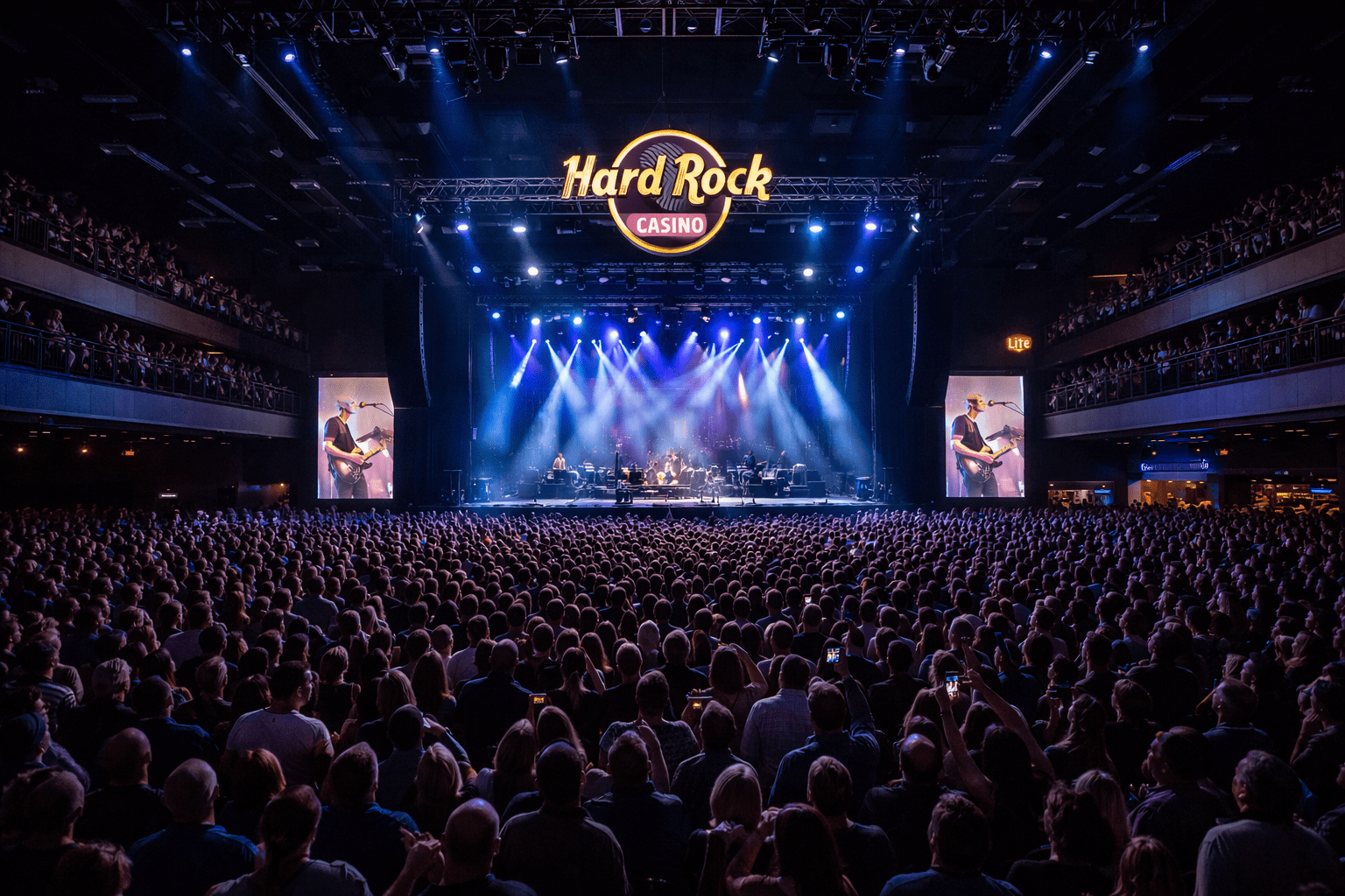Large crowd at a concert inside Hard Rock Casino, facing a brightly lit stage with the Hard Rock logo above.
